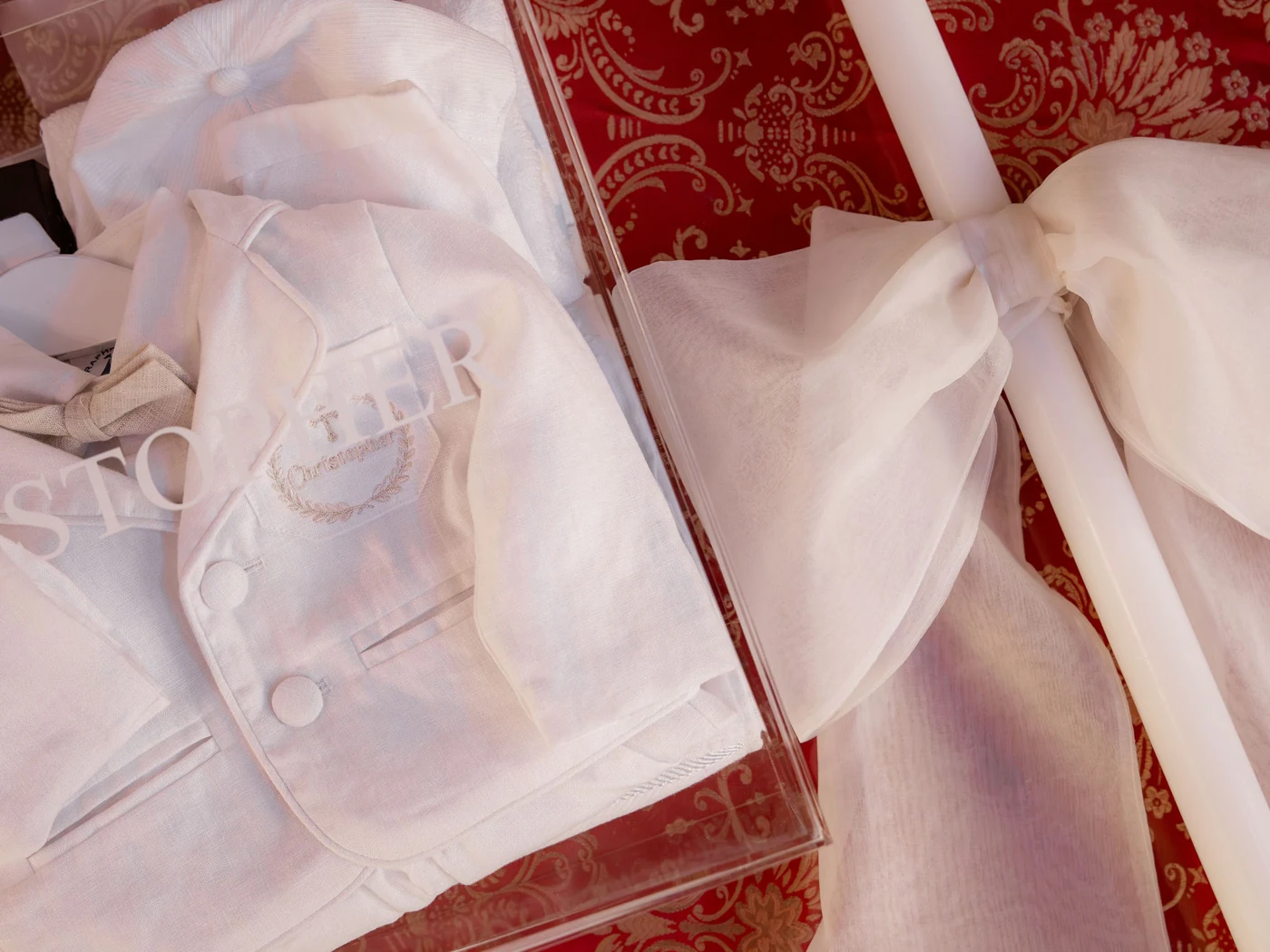 White christening attire and a ribbon-adorned candle arranged for the ceremony